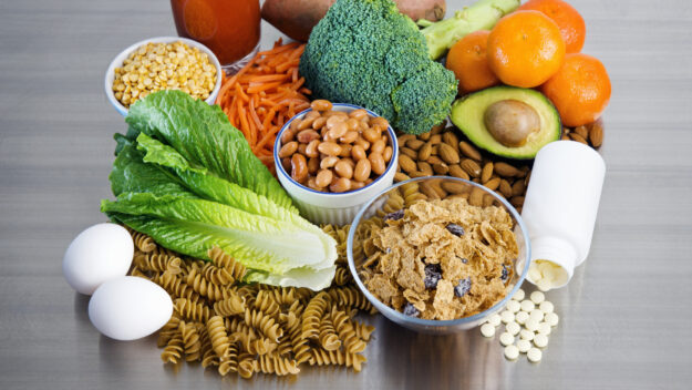 Folic Acid supplement and foods on stainless kitchen counter